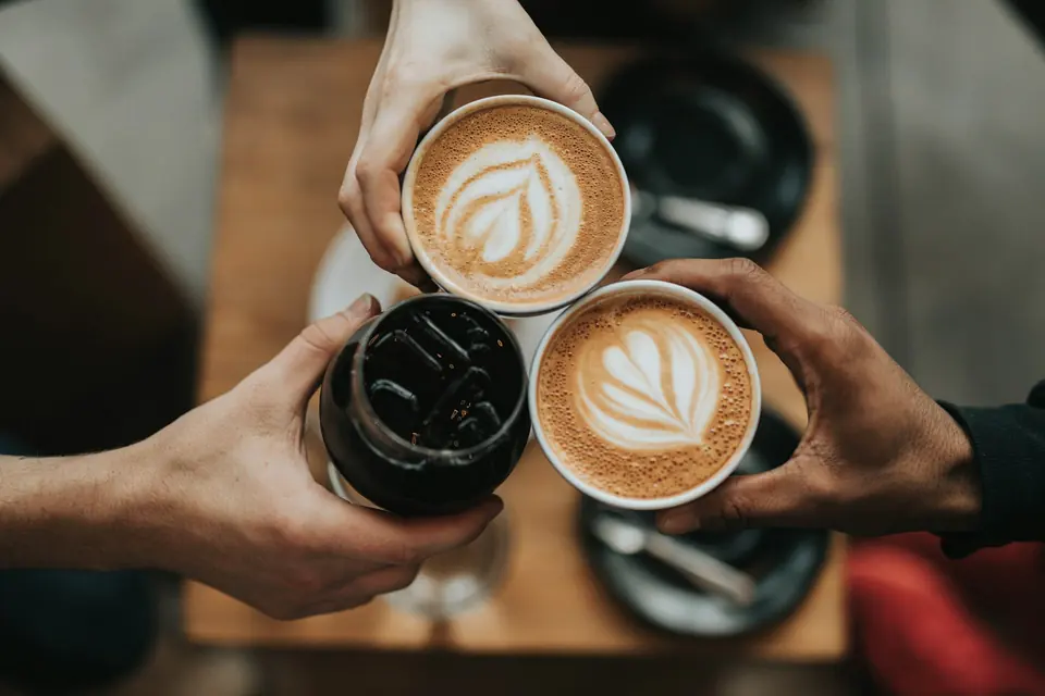 Three coffees with latte art held up in a small cluster.