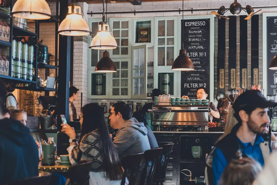 A busy specialty coffee shop interior with pendant lighting and a packed counter.