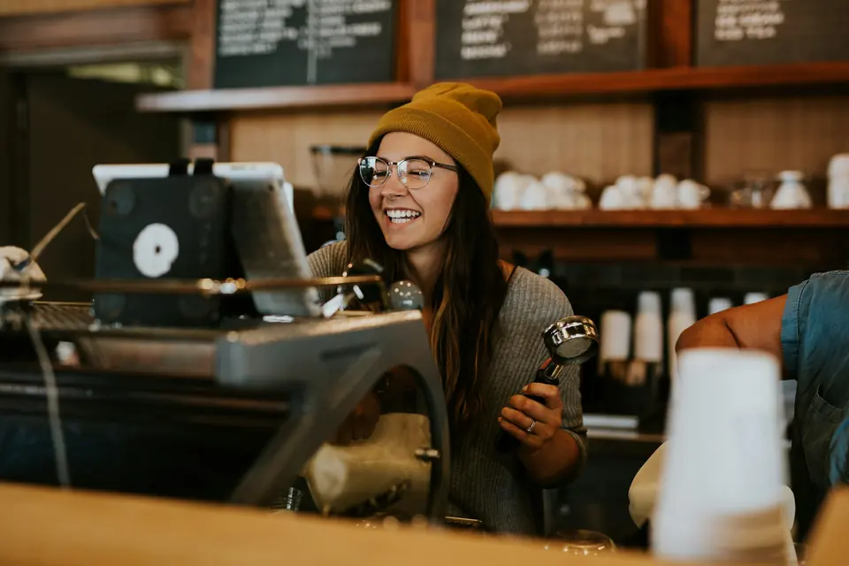 A barista at the Bramble counter, with brass espresso machine and cups behind.